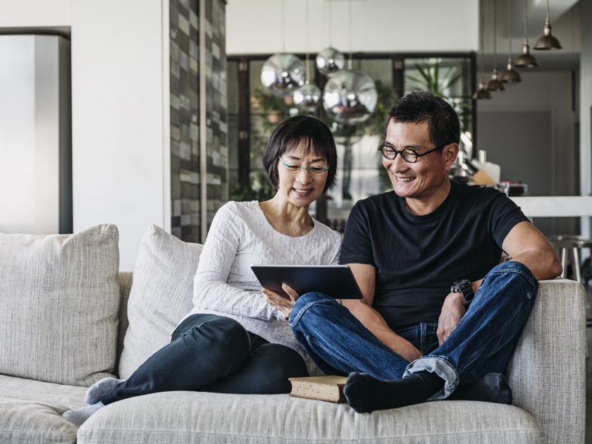 Man and woman on a couch looking at a tablet